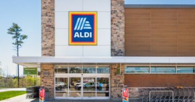 Aldi supermarket exterior with parking lot reflections in the glass entrance doors.