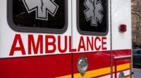 Close-up of an ambulance's side, showing the word "AMBULANCE" and the Star of Life.