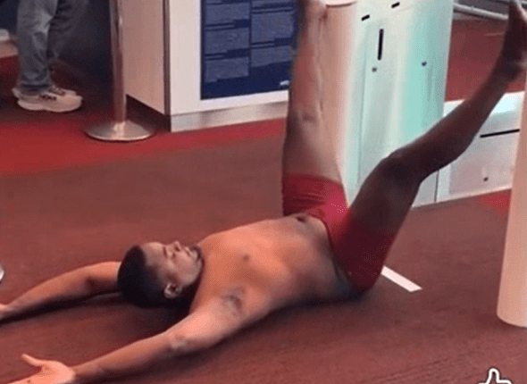 Man in red underwear lying on the floor at an airport gate.