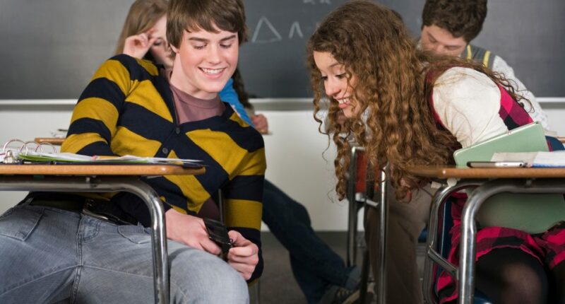 High school students text messaging in class.