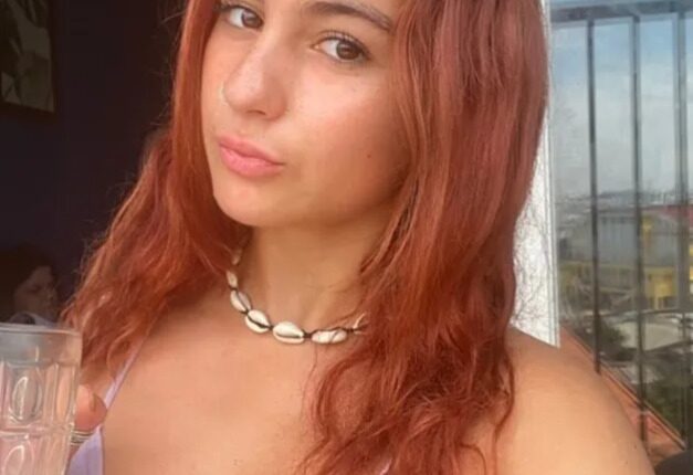 Woman with red hair on a balcony, enjoying a coffee break during her time teaching English in Vietnam.