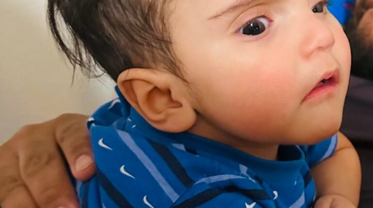 Photo of a baby wearing a blue shirt.