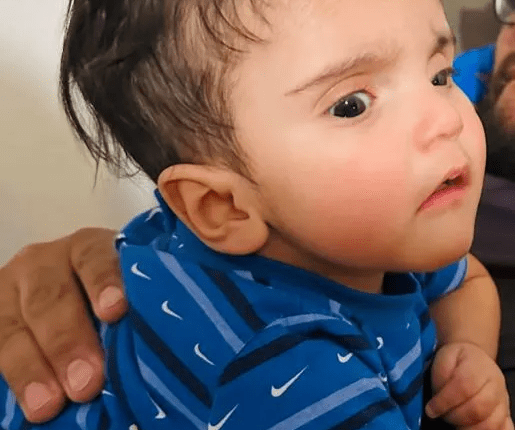 Photo of a baby wearing a blue shirt.