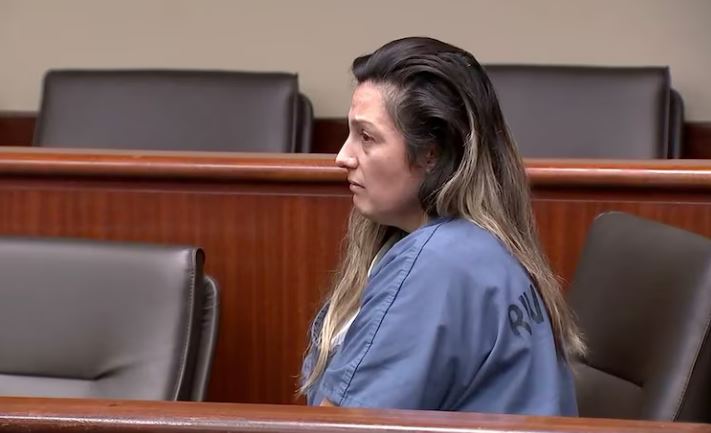Woman in a blue shirt sitting in a courtroom.