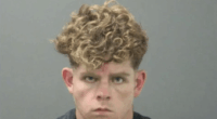Mugshot of a young man with curly blond hair.