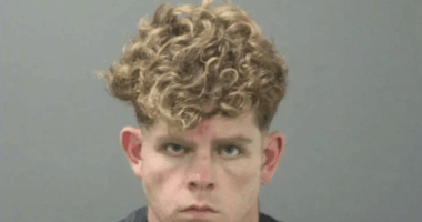 Mugshot of a young man with curly blond hair.