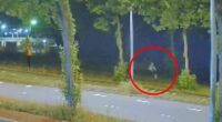 Nighttime security camera footage of a person running along a road.
