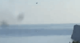Plane over lake and cliff.