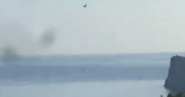 Plane over lake and cliff.