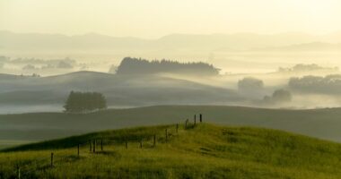 Misty sunrise over rolling hills and farmland.