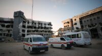 Ambulances parked outside damaged hospital buildings.