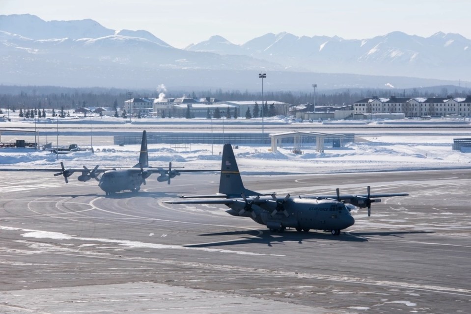 Two US Air Force C-130 Hercules aircraft on a snowy tarmac.