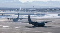 Two US Air Force C-130 Hercules aircraft on a snowy tarmac.