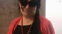 Photo of a woman wearing sunglasses and a red cardigan.