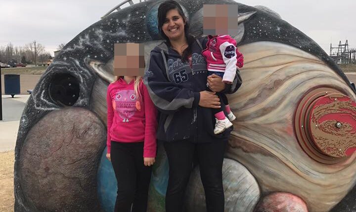 A woman and two children posing in front of a playground mural depicting planets.