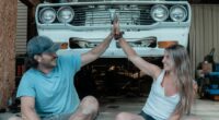Couple giving a high five in front of a car.