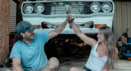 Couple giving a high five in front of a car.