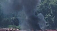 Smoke rising from a barge fire on a river.