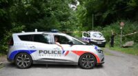 Police cars are parked in front of a cordoned-off area, near a sports field where a 32-year-old man was found dead with his throat slit and gutted, in Pont-de-Metz on August 4, 2025. The victim had stab wounds to the neck and back and has been found by a walker in a cross position, police told AFP. (Photo by Francois NASCIMBENI / AFP) (Photo by FRANCOIS NASCIMBENI/AFP via Getty Images)