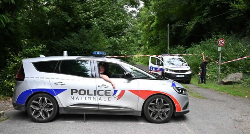 Police cars are parked in front of a cordoned-off area, near a sports field where a 32-year-old man was found dead with his throat slit and gutted, in Pont-de-Metz on August 4, 2025. The victim had stab wounds to the neck and back and has been found by a walker in a cross position, police told AFP. (Photo by Francois NASCIMBENI / AFP) (Photo by FRANCOIS NASCIMBENI/AFP via Getty Images)
