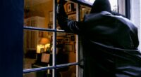 A burglar breaking into a house through a window.
