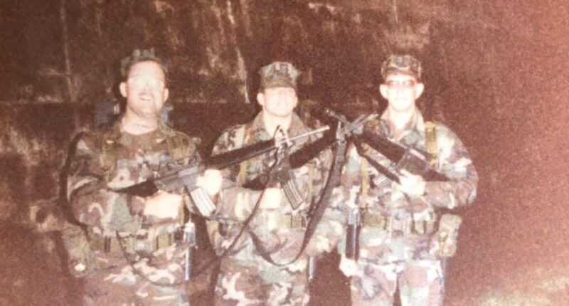 Three soldiers in camouflage uniforms holding rifles.