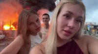 Two young women filming themselves in front of a burning oil depot.