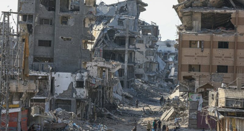 Destroyed buildings and people walking through rubble in Shujaiyya, Gaza.