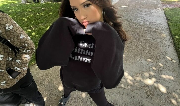 Teenager in black sweatshirt posing outdoors.