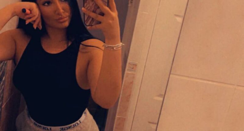 Selfie of a woman in a black top and gray sweatpants.