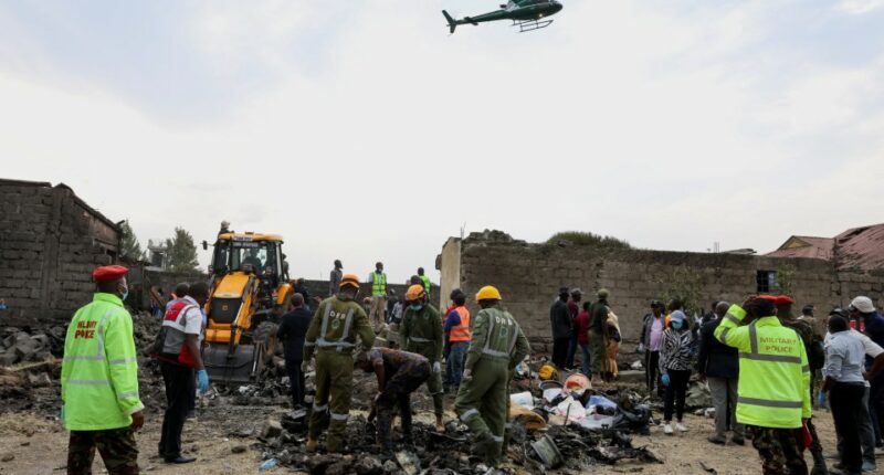 Emergency personnel and a helicopter at the site of a plane crash.