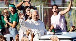 Pope Leo XIV waving from a popemobile to young people at a Jubilee of Youth Mass.