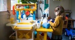 A little girl playing with a toy kitchen.