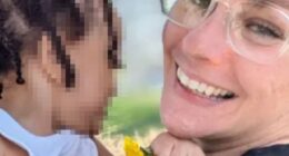 Photo of a smiling woman holding a toddler.