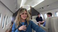 Woman seated in a private jet with two men in the background.