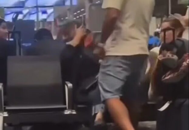 A man slapping a woman in an airport terminal.