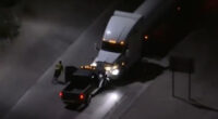 Aerial view of a police chase at night, showing a semi-truck and a smaller vehicle.