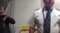 Police officer escorting a pilot from a cockpit.