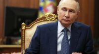 Vladimir Putin sitting at a table.