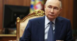 Vladimir Putin sitting at a table.