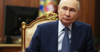 Vladimir Putin sitting at a table.