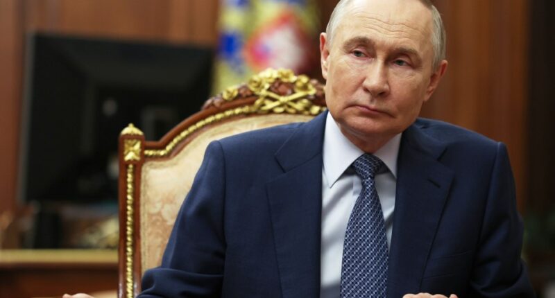 Vladimir Putin sitting at a table.