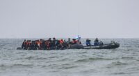 Migrants in a boat being followed by a French Maritime Gendarmerie boat in the English Channel.