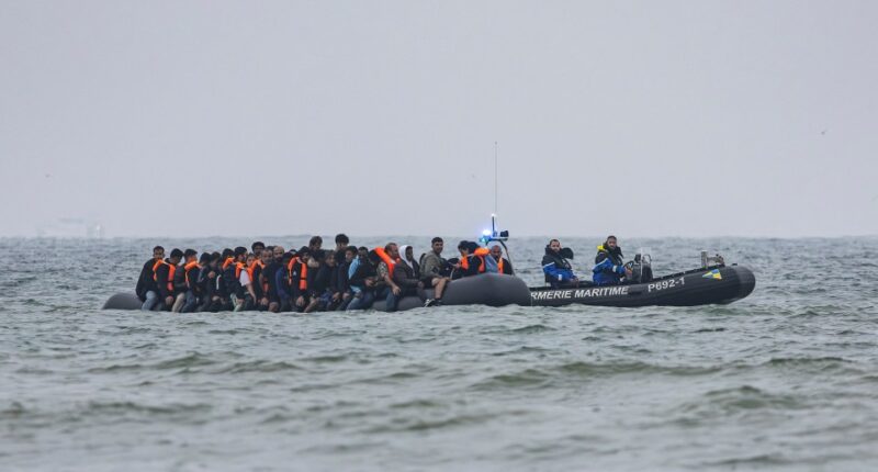Migrants in a boat being followed by a French Maritime Gendarmerie boat in the English Channel.