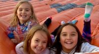 Three young girls smiling on a large inflatable.