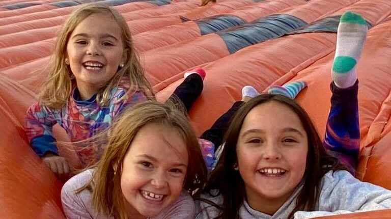 Three young girls smiling on a large inflatable.