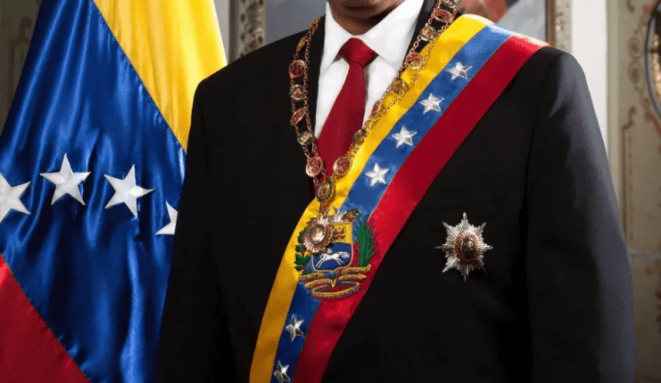 Nicolás Maduro in formal wear with Venezuelan flag.