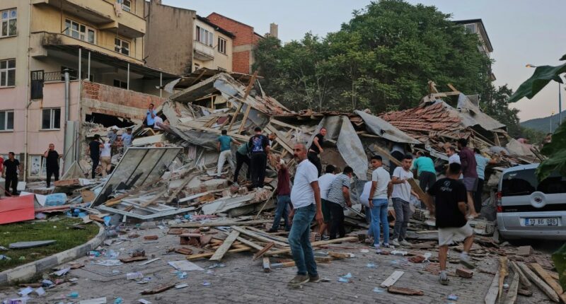 People removing debris from a collapsed building after an earthquake.