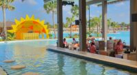 Swim-up bar at a resort with a large pool and yellow sun structure.