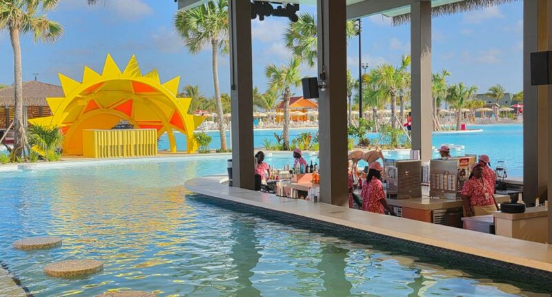 Swim-up bar at a resort with a large pool and yellow sun structure.